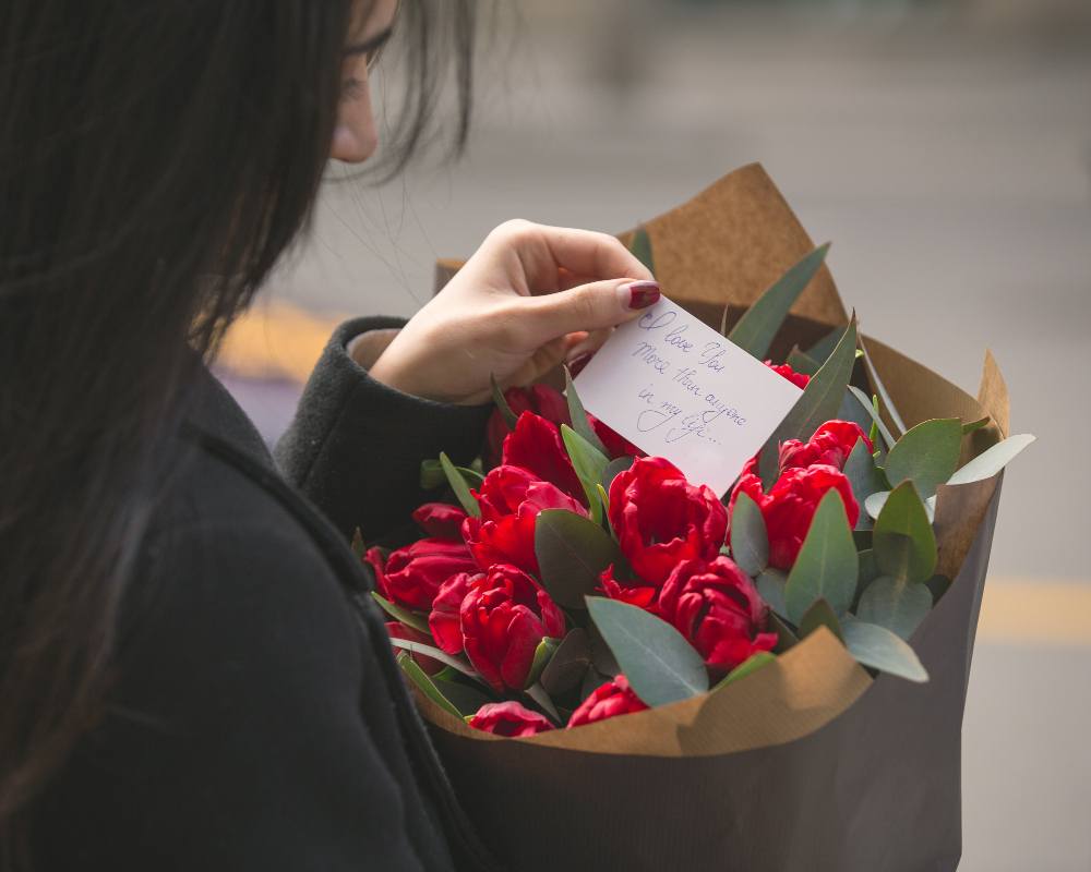 girl-reading-note-put-into-bouquet-red-tulips